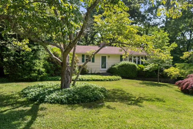 a front view of a house with a yard and trees