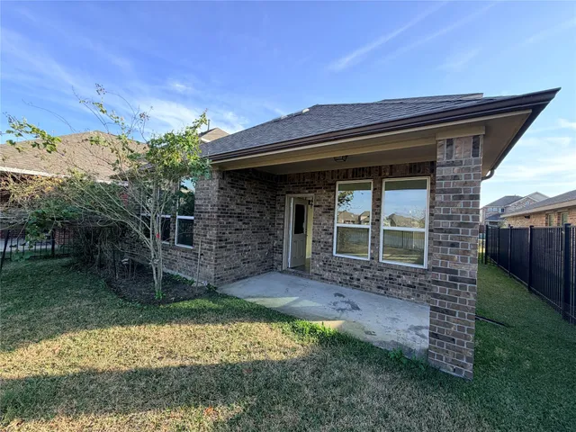 a backyard of a house with table and chairs under an umbrella