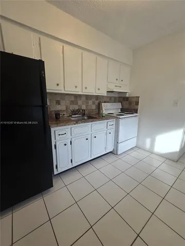 a kitchen with granite countertop white cabinets and stainless steel appliances