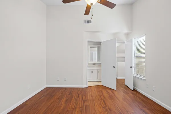 an empty room with wooden floor cabinet and windows