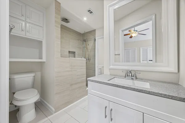 a bathroom with a granite countertop sink a toilet and a mirror