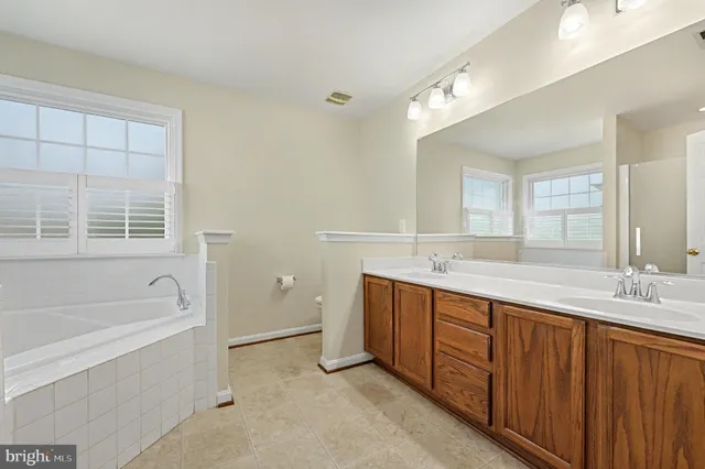 a spacious bathroom with a tub sink and mirror