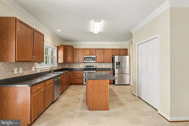 a large kitchen with stainless steel appliances kitchen island granite countertop wooden cabinets a granite counter top and a sink