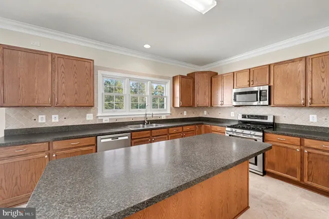 a kitchen with stainless steel appliances granite countertop a stove a sink and a microwave