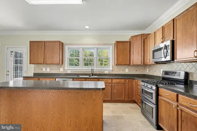a kitchen with stainless steel appliances granite countertop a sink stove and microwave