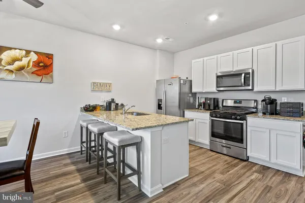 a kitchen with stainless steel appliances kitchen island granite countertop a table chairs microwave and sink