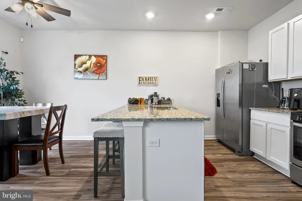 a kitchen with stainless steel appliances a dining table chairs and wooden floor