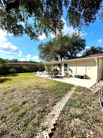 a view of swimming pool with lawn chairs and large trees