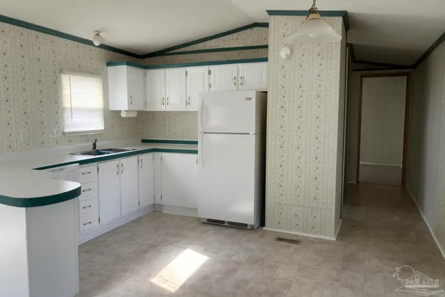 a kitchen with granite countertop a sink refrigerator and cabinets