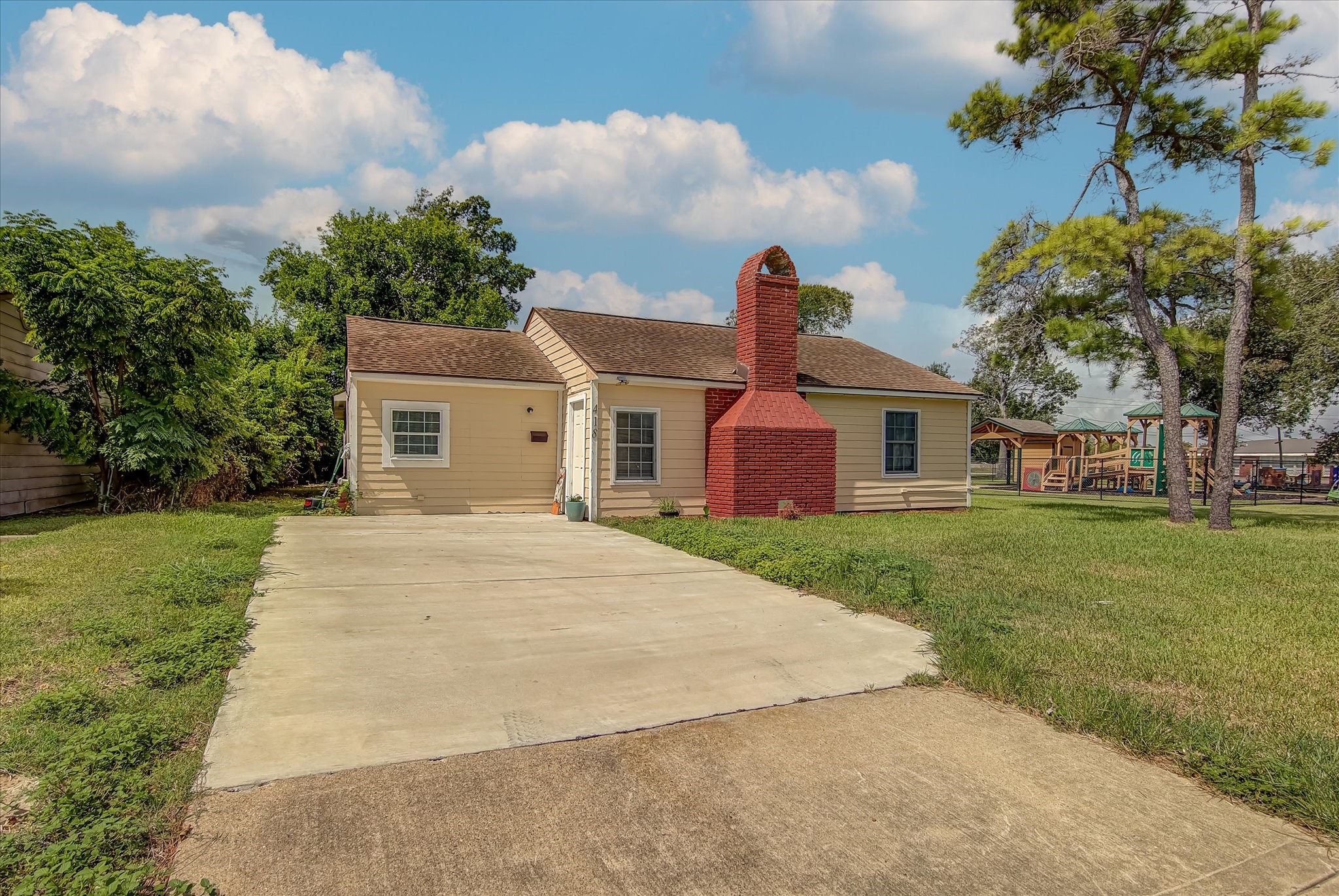 418 Azalea Street Lake Jackson, TX 77566 - Photo 6 of 34 Charming single-story home with a spacious driveway and a distinctive red brick chimney. The exterior features light-color siding and a well-maintained lawn, offering a cozy and welcoming atmosphere. Ideal for first-time buyers or investors
