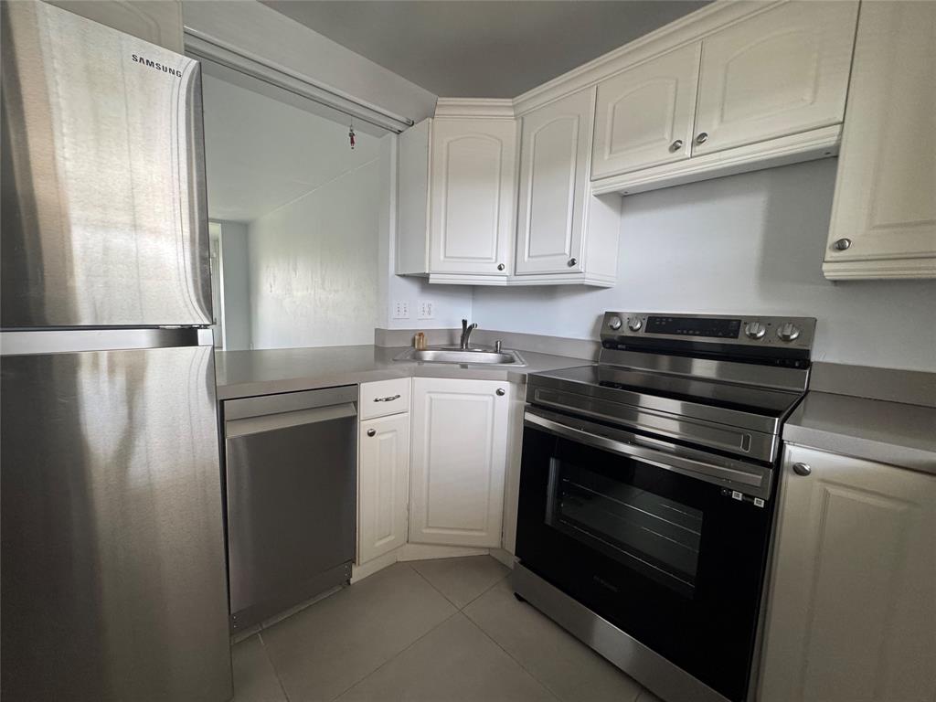 9235 A Lagoon Place, Unit 310 Davie, FL 33324 - Photo 4 of 32 a kitchen with a refrigerator stove and white cabinets