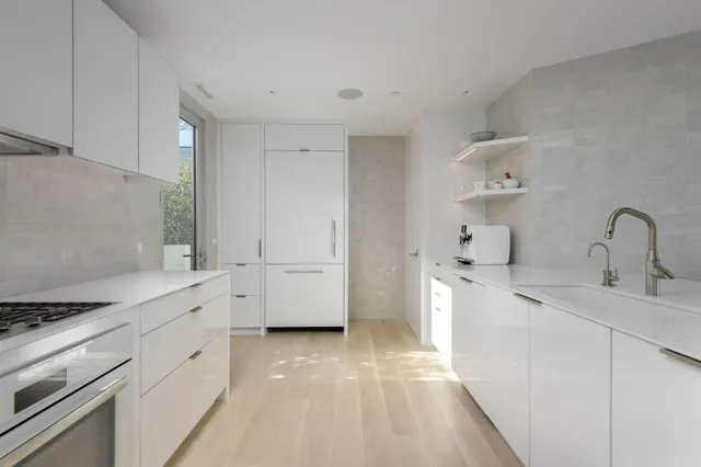 a kitchen with white cabinets a sink stove and refrigerator