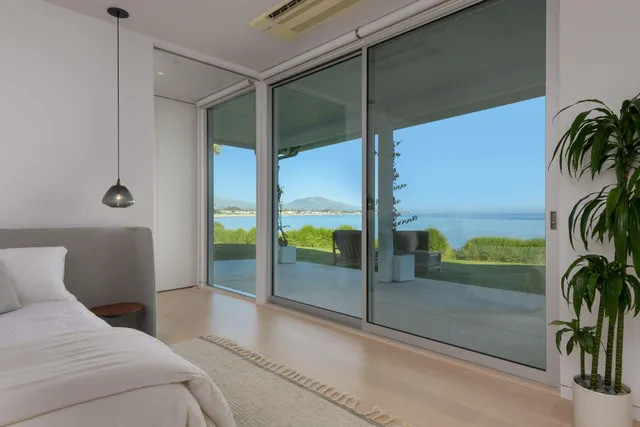 a bedroom with a balcony a bed and a potted plant