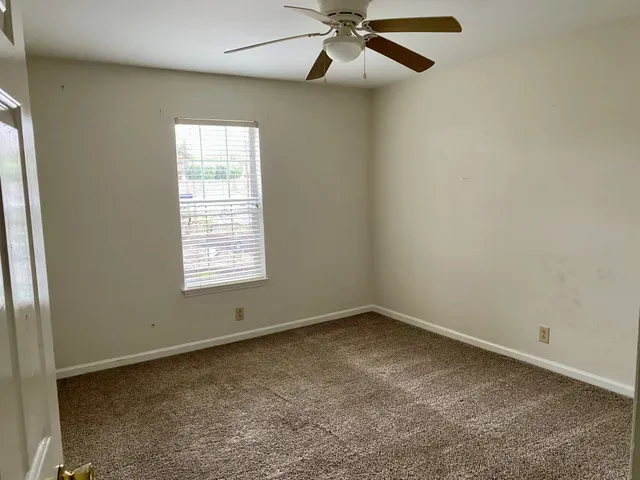 an empty room with a window and a fan