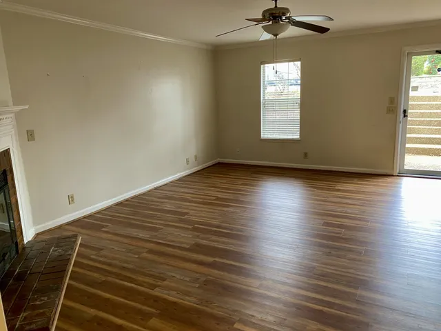 an empty room with wooden floor cabinet and windows