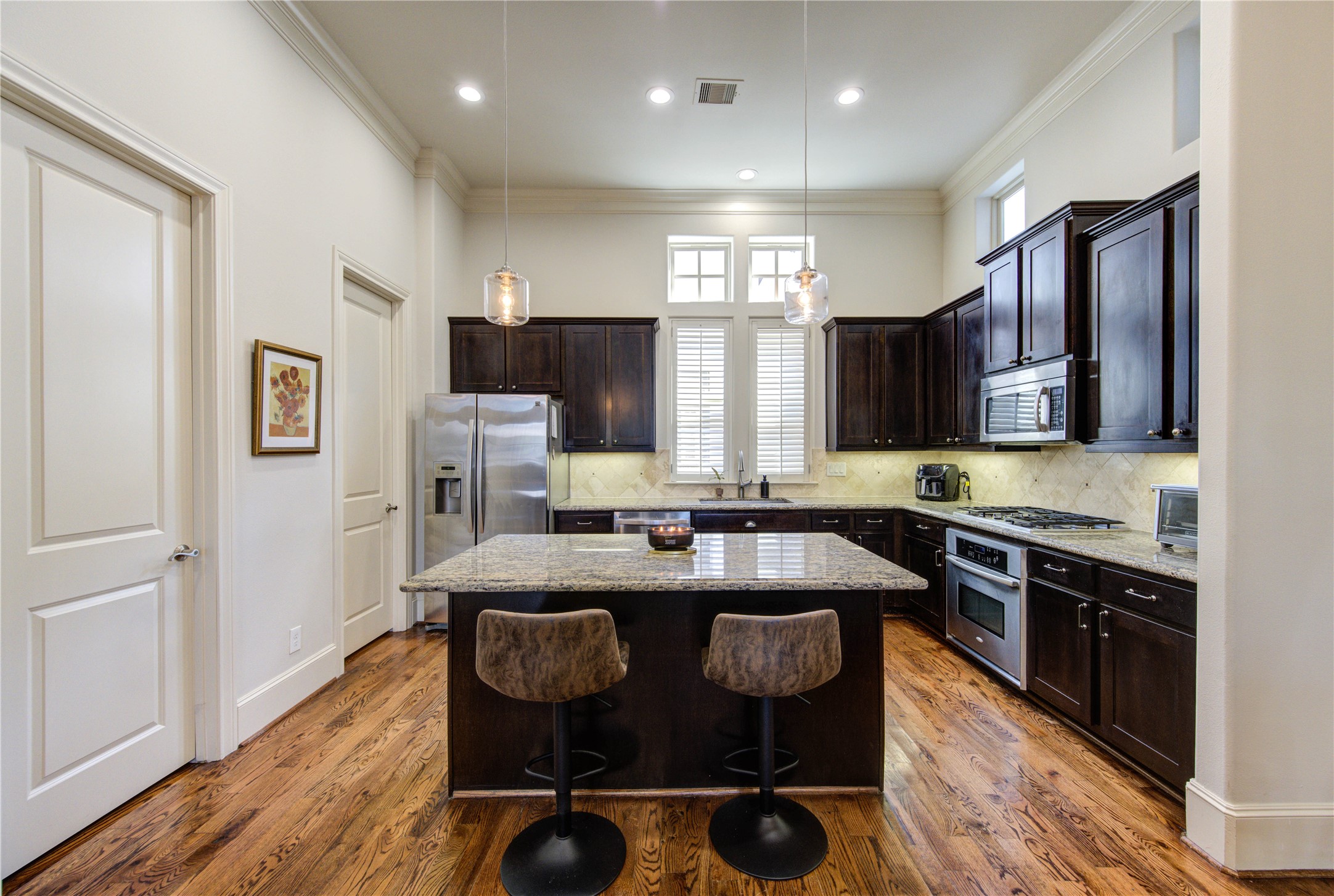 411 West 17th Street, Unit B Houston, TX 77008 - Photo 24 of 50 a kitchen with stainless steel appliances granite countertop a stove a sink dishwasher a microwave oven and a refrigerator with wooden floor