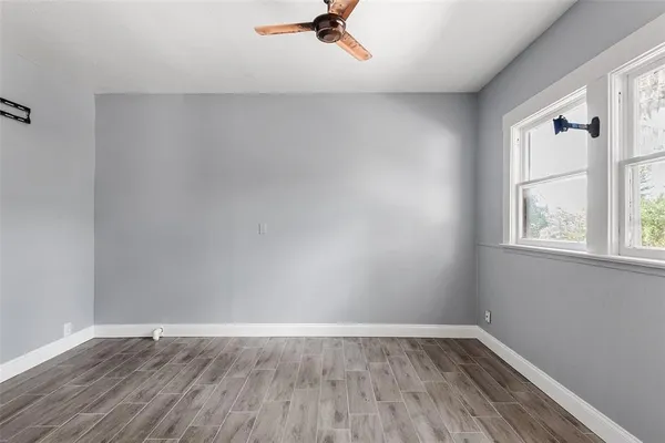 an empty room with wooden floor and windows