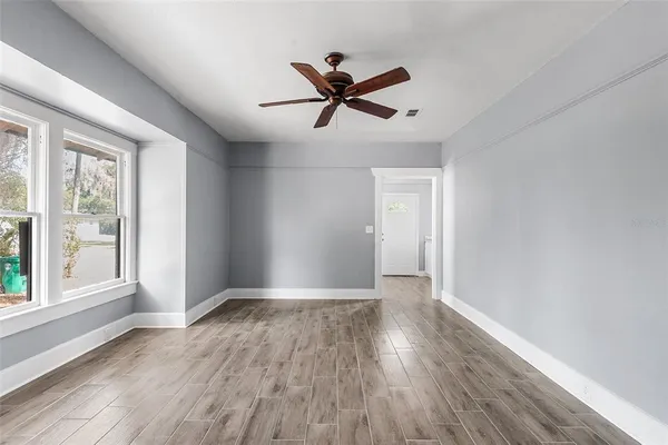 a view of empty room with wooden floor and fan
