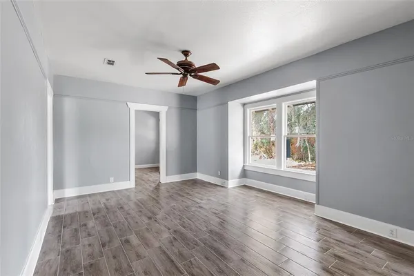 a view of an empty room with a window and wooden floor