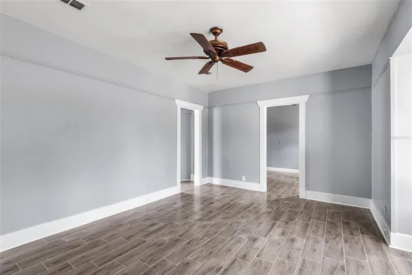 an empty room with wooden floor and a ceiling fan