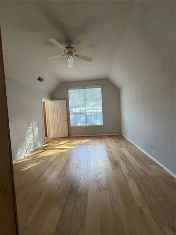 an empty room with wooden floor chandelier fan and windows