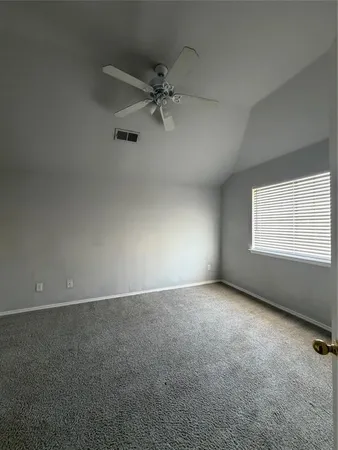 an empty room with a window and a fan