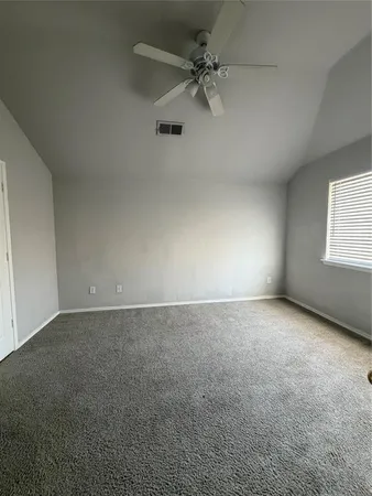 an empty room with a window and a ceiling fan