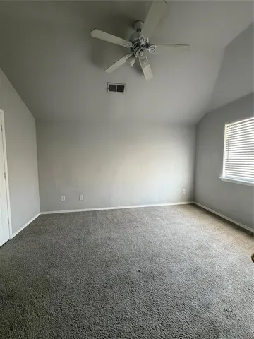 an empty room with a window and a ceiling fan