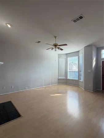 an empty room with windows and fan