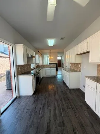 a kitchen with a hard wood floor white cabinets and white appliances