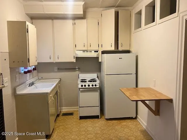 a kitchen with stainless steel appliances granite countertop a refrigerator sink stove and white cabinets