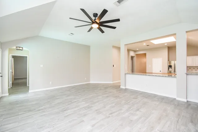 a view of empty room with wooden floor and ceiling fan