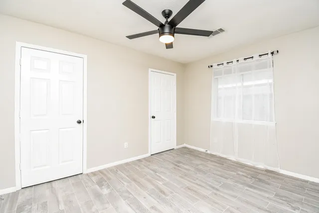 a view of a room with wooden floor and a ceiling fan