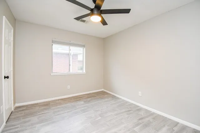 an empty room with a window and a fan