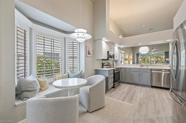 a room with kitchen island stainless steel appliances a sink and a large window