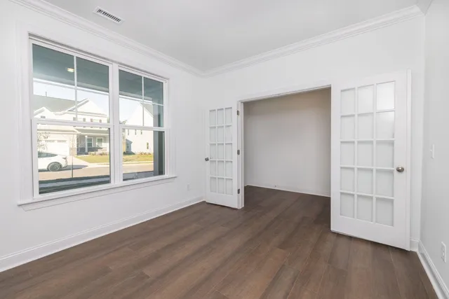an empty room with wooden floor and windows