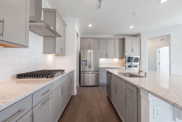 a kitchen with granite countertop a sink a stove cabinets and wooden floor