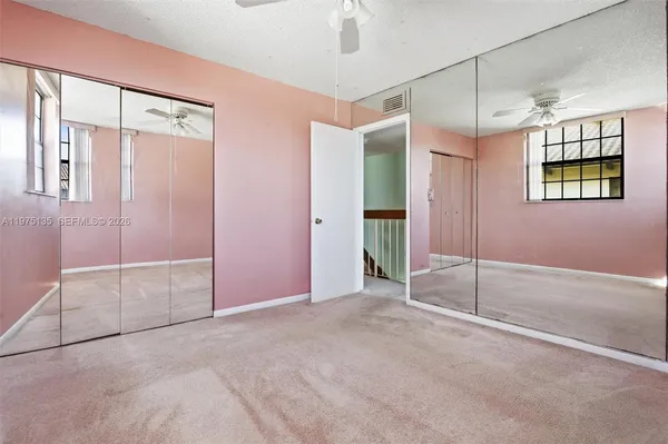 a view of an empty room with window and chandelier fan