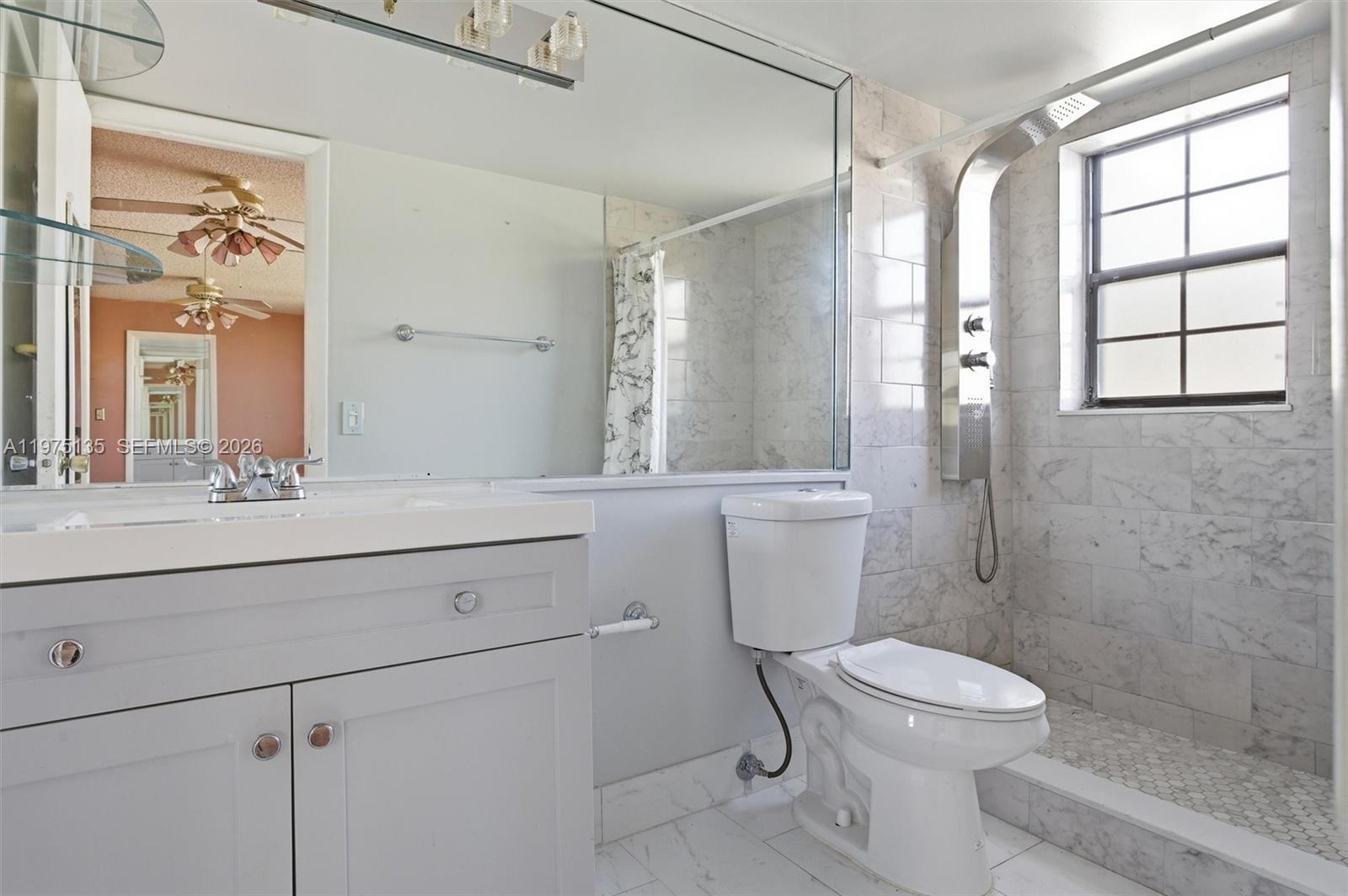 12253 Southwest 16th Terrace, Unit 108M Miami, FL 33175 - Photo 30 of 50 a bathroom with a sink a toilet a mirror and a window