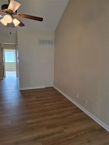 a view of an empty room with window and wooden floor