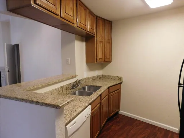 a utility room with granite countertop a sink and dishwasher