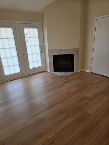 an empty room with wooden floor fireplace and windows