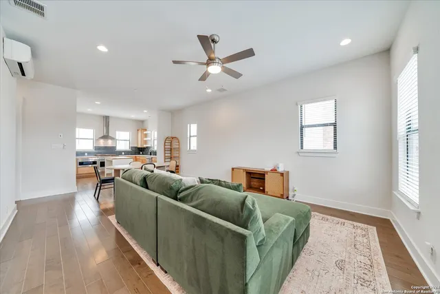 a living room with furniture and a dining table with wooden floor