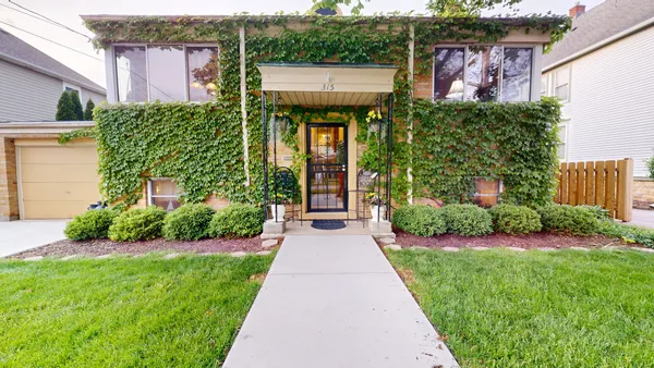 a front view of a house with a yard and potted plants