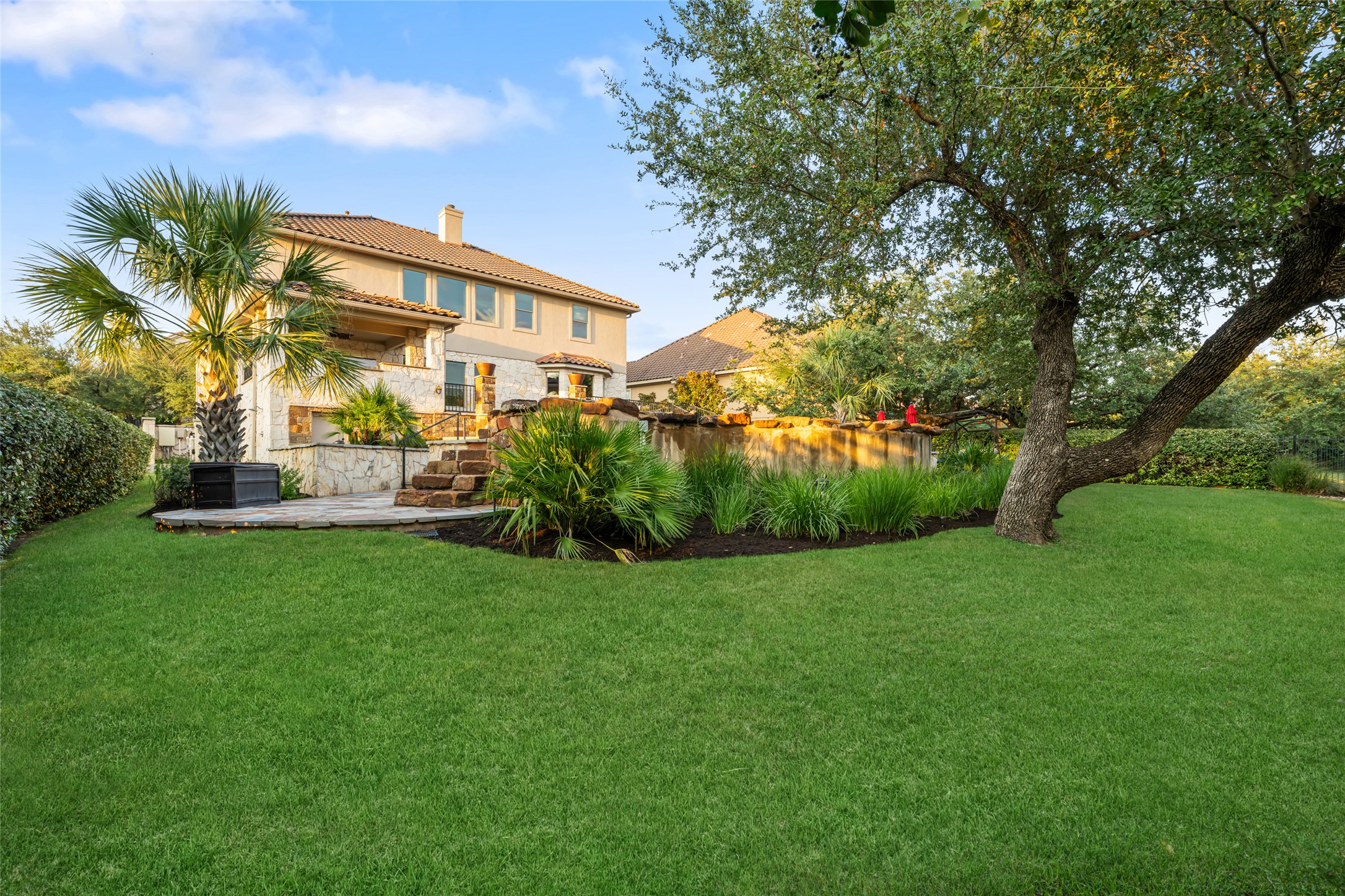 15205 Spillman Ranch Loop Austin, TX 78738 - Photo 8 of 40 A verdant lawn gracefully transitions to a stone patio, embracing a tranquil pool and stately home.