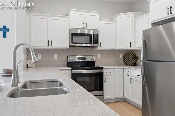 a kitchen with stainless steel appliances granite countertop a refrigerator sink and white cabinets