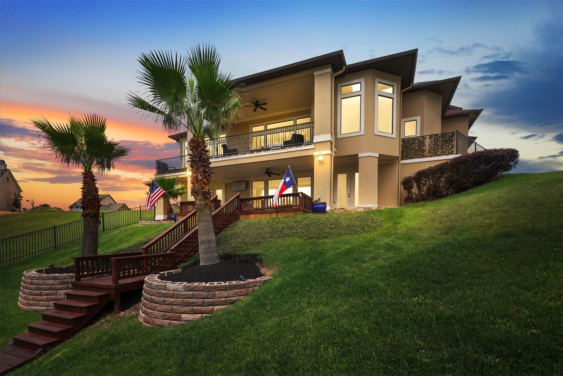 10896 Decatur Street Willis, TX 77318 - Photo 1 of 50 This exquisite two-story home boasts modern design with large windows and a spacious balcony, nestled on a lush lawn with palm trees and a pristine pathway, offering serene sunset views.