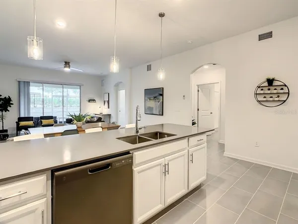a kitchen with a sink dishwasher and white cabinets with wooden floor