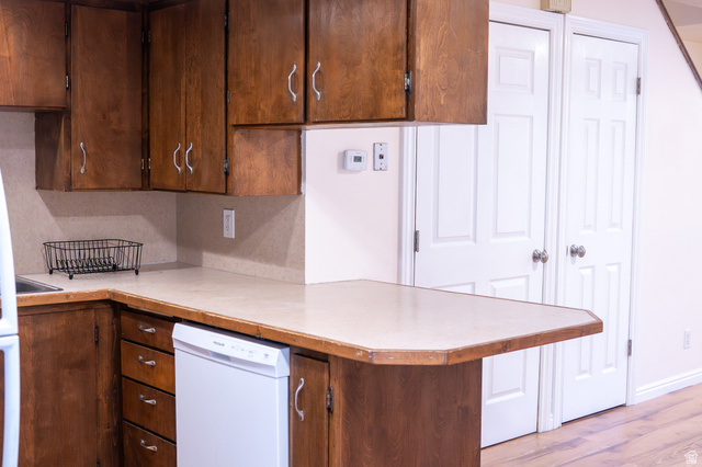 1269 North 400 East, Unit 3 Logan, UT 84341 - Photo 12 of 23 Kitchenette featuring a wood-finish peninsula countertop, integrated white dishwasher, wood-finish cabinetry with silver hardware, and a light-toned backsplash