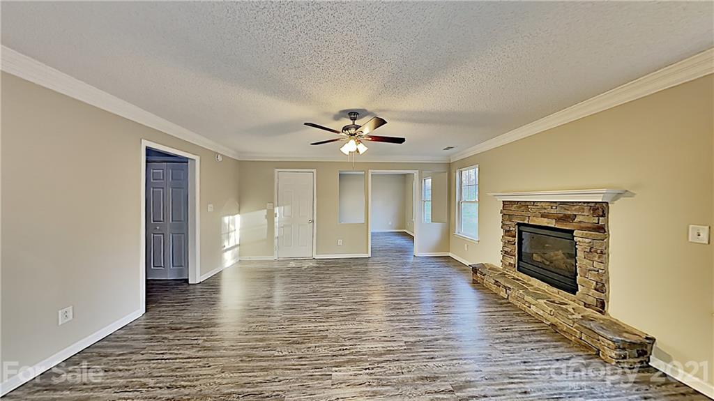 825 Raindrops Road Gastonia, NC 28054 - Photo 4 of 23 an empty room with wooden floor fireplace and windows